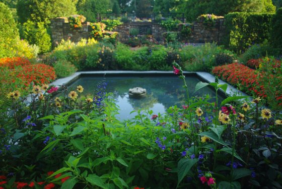 A square fountain surrounded but late summer flowers at Longwood Gardens.